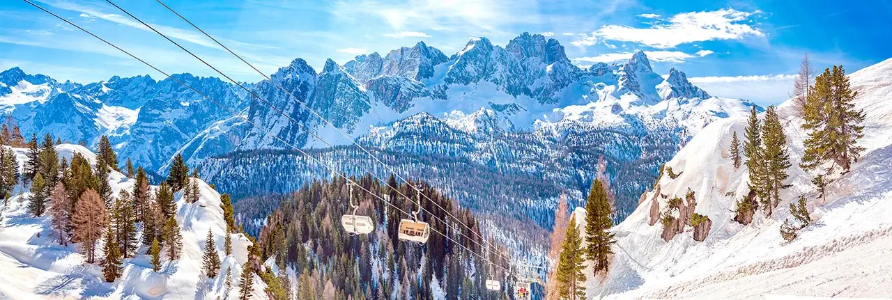 Funivia sopra le piste innevate delle Dolomiti