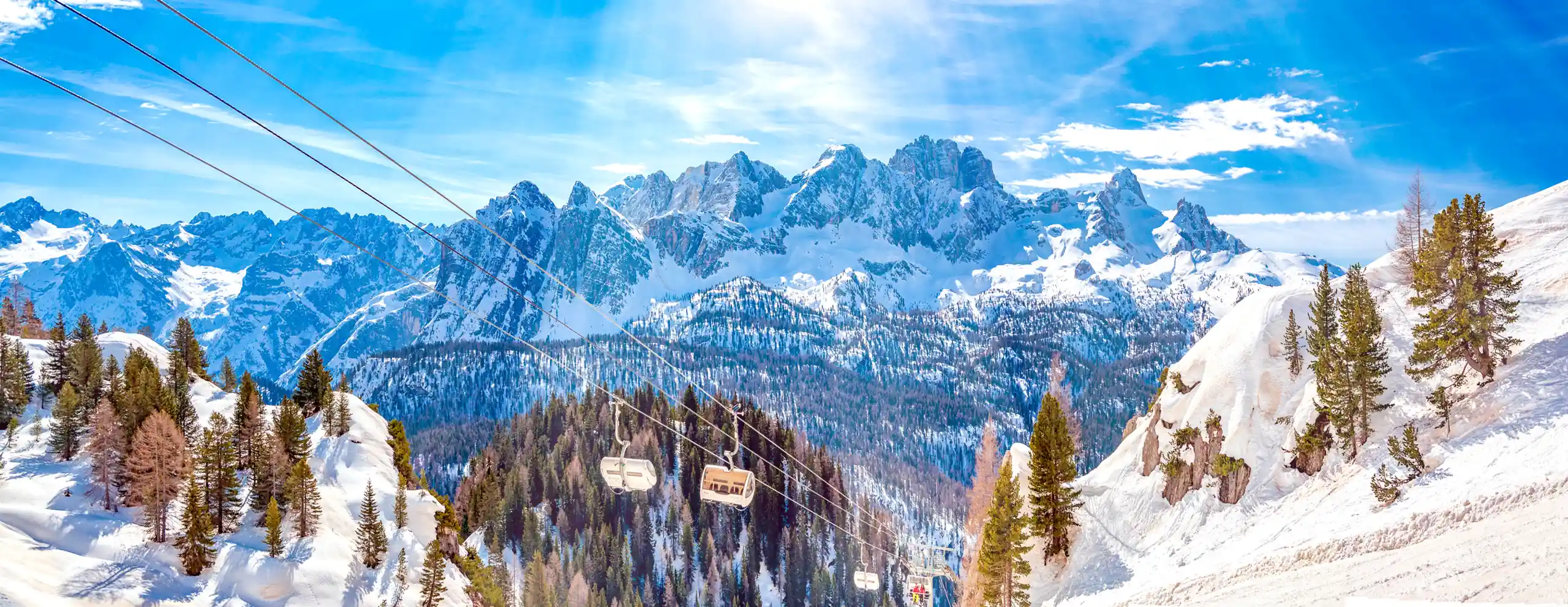 Cabinovia sopra i boschi innevati con le Dolomiti sullo sfondo